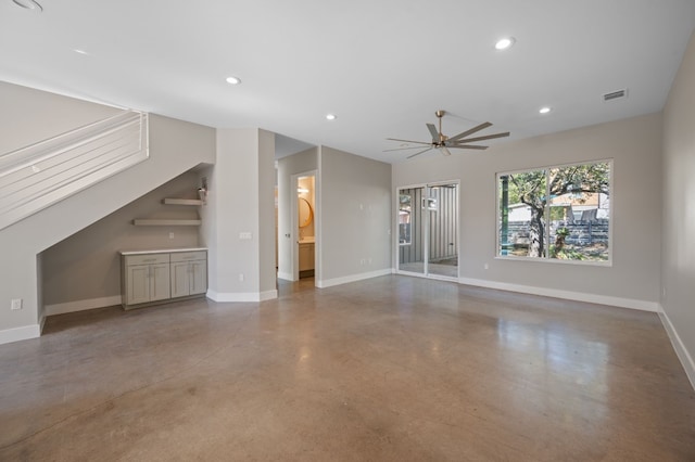 unfurnished living room with ceiling fan and concrete floors