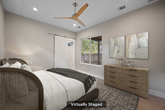 bedroom featuring a barn door, dark carpet, and ceiling fan