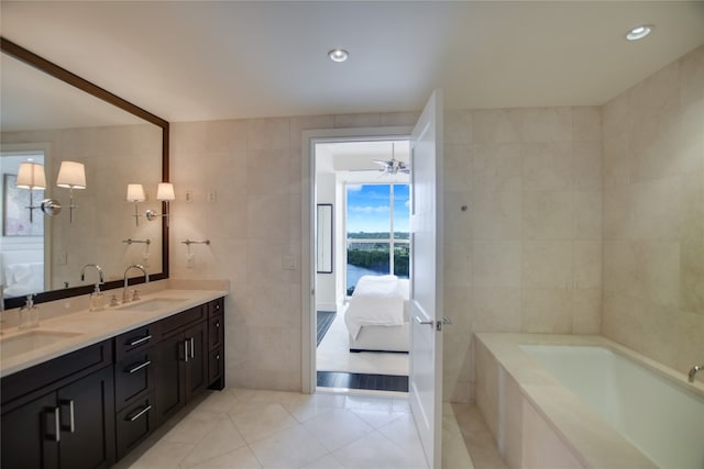 bathroom with ceiling fan, tile patterned flooring, vanity, and tile walls