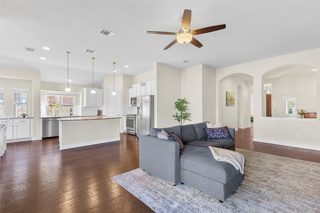 living room with ceiling fan and dark wood-type flooring