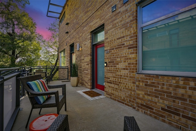 patio terrace at dusk featuring a balcony