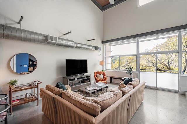 living room with a wealth of natural light, concrete floors, and a high ceiling