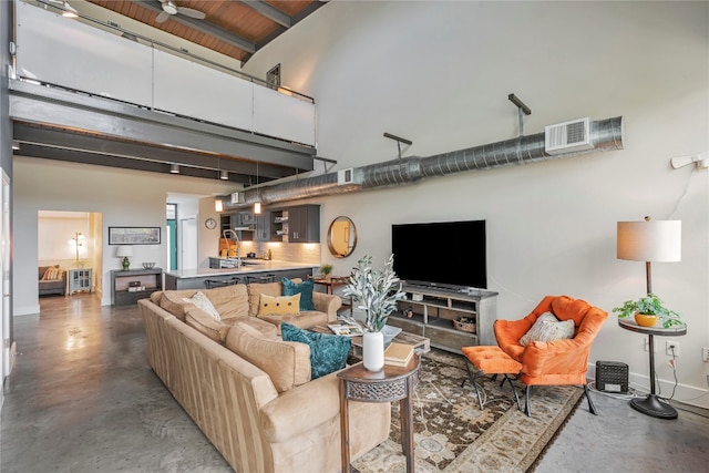 living room featuring ceiling fan, concrete flooring, and a high ceiling