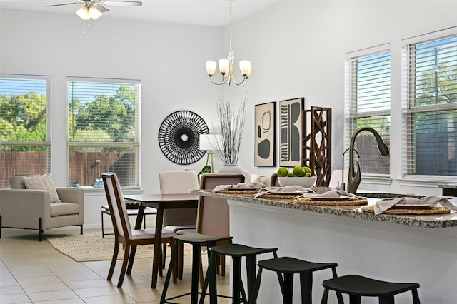 dining space with light tile patterned floors, ceiling fan with notable chandelier, and vaulted ceiling