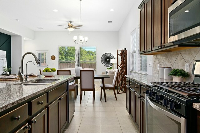 kitchen with sink, light stone countertops, appliances with stainless steel finishes, tasteful backsplash, and dark brown cabinets