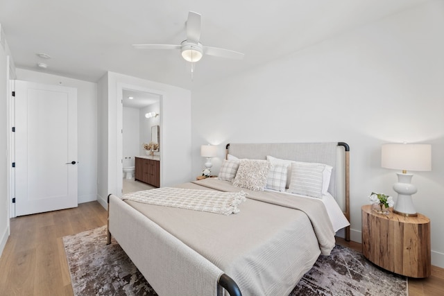 bedroom featuring hardwood / wood-style floors, ceiling fan, and ensuite bath