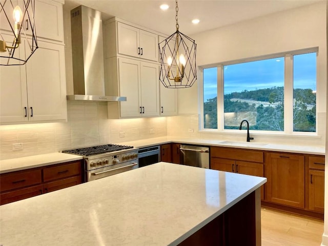 kitchen with tasteful backsplash, brown cabinetry, appliances with stainless steel finishes, wall chimney range hood, and a sink