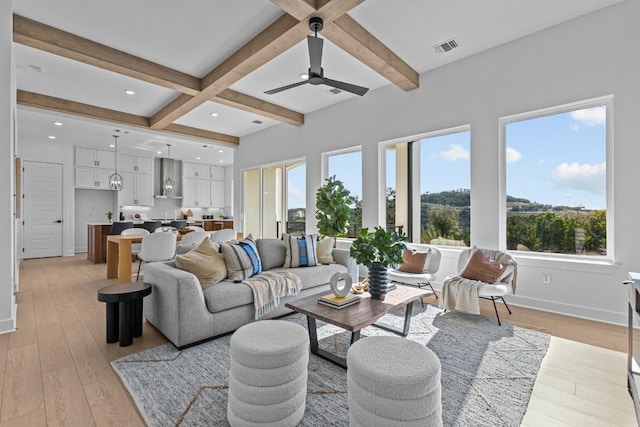 living area featuring visible vents, beam ceiling, a ceiling fan, and light wood finished floors