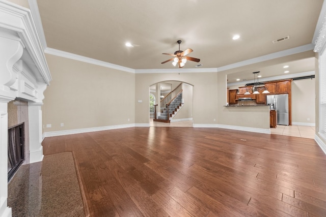 unfurnished living room with light hardwood / wood-style floors, ceiling fan, and crown molding