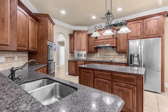 kitchen with decorative light fixtures, ornamental molding, a center island, and appliances with stainless steel finishes