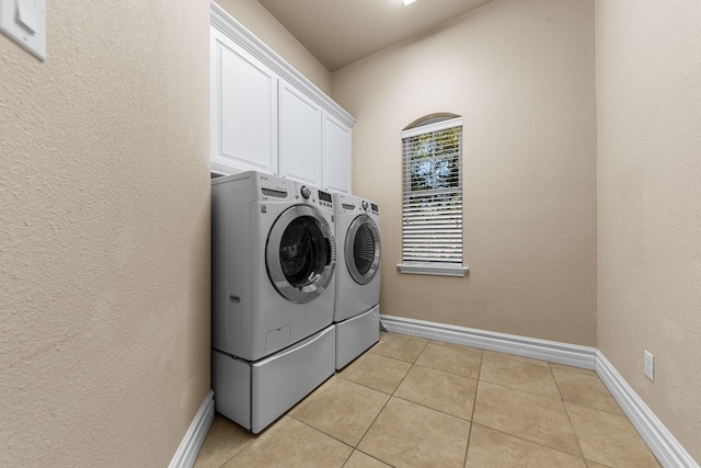 washroom with cabinets, light tile patterned floors, and washer and dryer