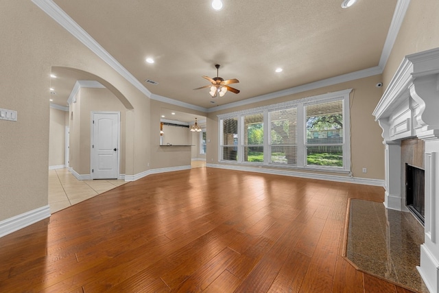 unfurnished living room with ceiling fan, crown molding, light wood-type flooring, and a textured ceiling