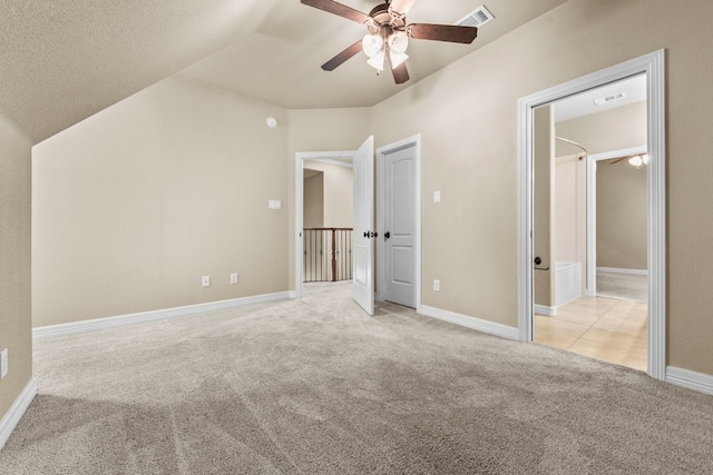 unfurnished bedroom with light carpet, a textured ceiling, vaulted ceiling, and ceiling fan