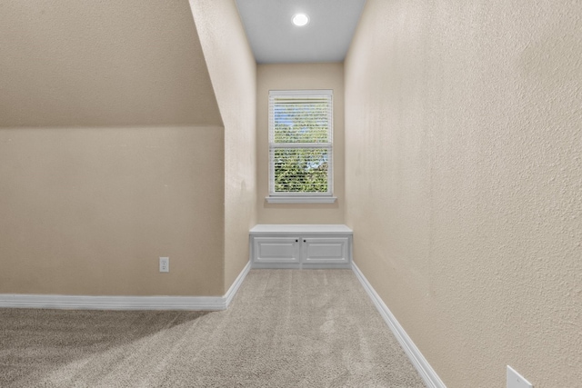 corridor featuring lofted ceiling and light colored carpet