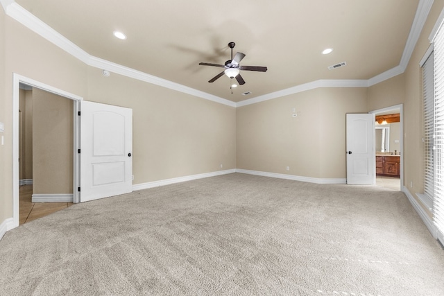 unfurnished bedroom featuring ceiling fan, ensuite bathroom, light colored carpet, and ornamental molding