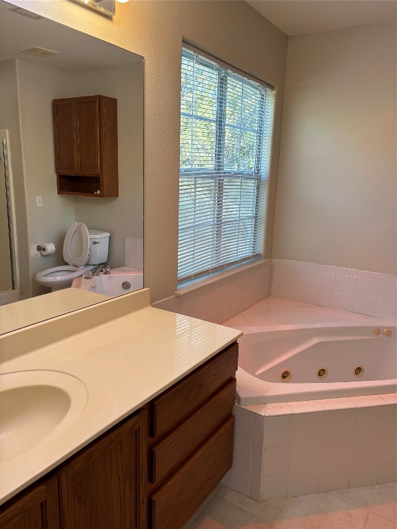 bathroom featuring tile patterned flooring, vanity, toilet, and tiled tub