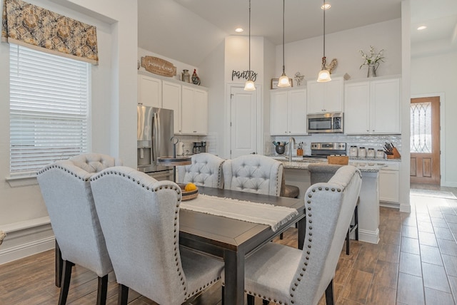 dining space featuring high vaulted ceiling, sink, and dark wood-type flooring