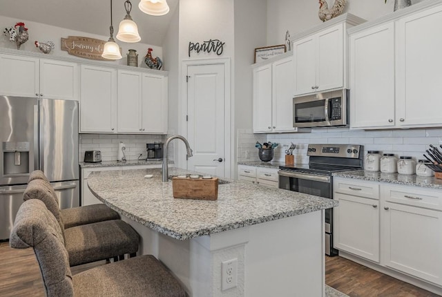 2104 Highland Ridge Rd, Georgetown, TX 78628 - kitchen featuring stainless steel appliances, decorative backsplash, an island with sink, a breakfast bar, and white cabinets
