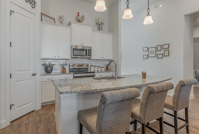 kitchen featuring white cabinetry, a center island with sink, hanging light fixtures, and appliances with stainless steel finishes