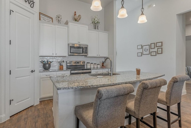 2104 Highland Ridge Rd, Georgetown, TX 78628 - kitchen featuring appliances with stainless steel finishes, decorative backsplash, dark wood-style floors, light stone counters, and a breakfast bar area