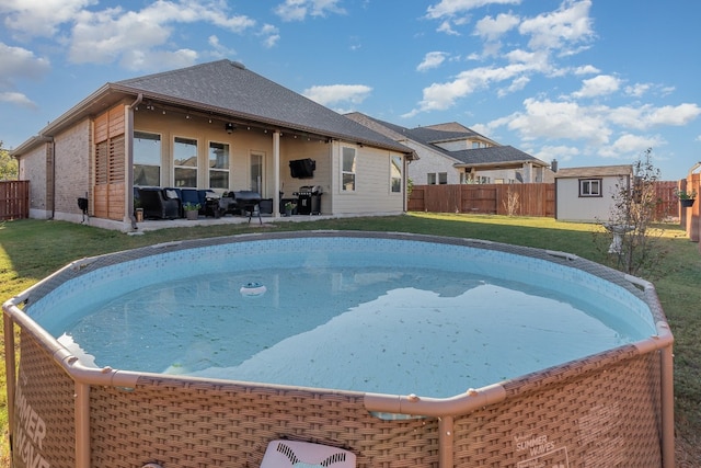 view of swimming pool with a lawn, area for grilling, and a storage unit