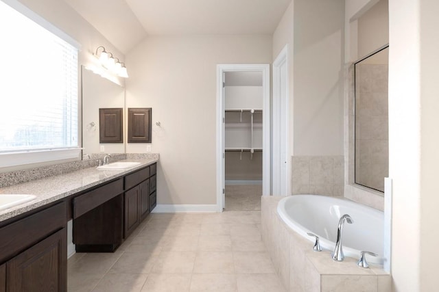 bathroom with tiled bath, tile patterned flooring, vanity, and vaulted ceiling