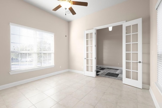 tiled spare room featuring ceiling fan and french doors