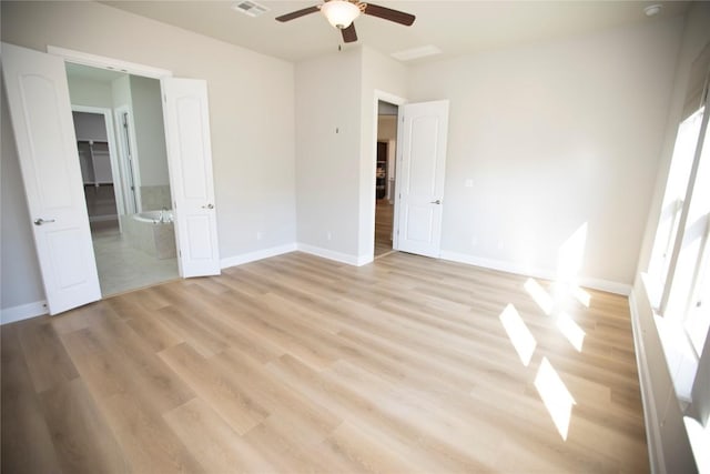 unfurnished bedroom with a closet, light hardwood / wood-style floors, ensuite bath, and ceiling fan