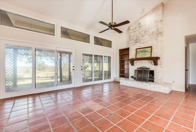 unfurnished living room featuring tile patterned floors, high vaulted ceiling, plenty of natural light, and a stone fireplace