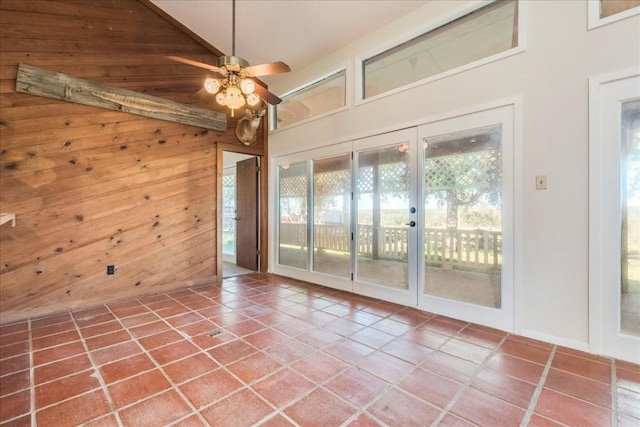 tiled spare room with ceiling fan, wood walls, and vaulted ceiling