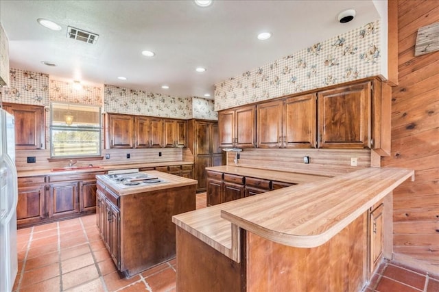 kitchen with kitchen peninsula, backsplash, a kitchen island, and wood walls