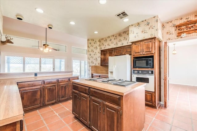 kitchen featuring dark brown cabinets, white appliances, ceiling fan, light tile patterned floors, and a kitchen island