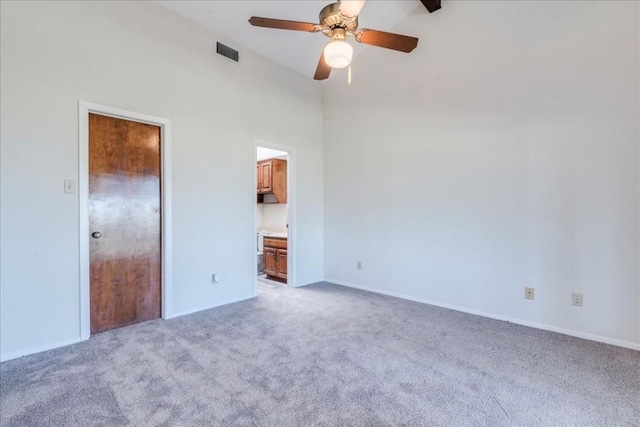 unfurnished bedroom featuring ceiling fan, light colored carpet, a towering ceiling, and connected bathroom