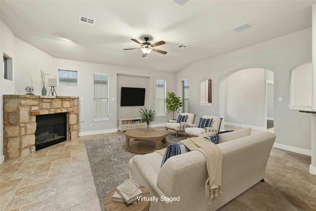 living room with ceiling fan, lofted ceiling, and a fireplace