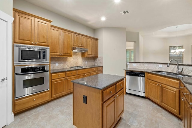 kitchen featuring dark stone counters, sink, a kitchen island, pendant lighting, and stainless steel appliances