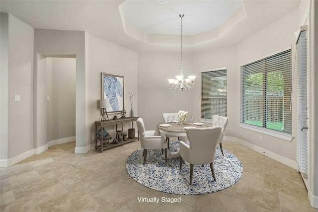 dining space featuring a tray ceiling and a notable chandelier