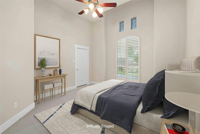 carpeted bedroom with a towering ceiling and ceiling fan