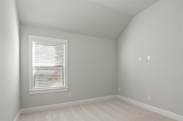 spare room featuring light carpet, plenty of natural light, and lofted ceiling