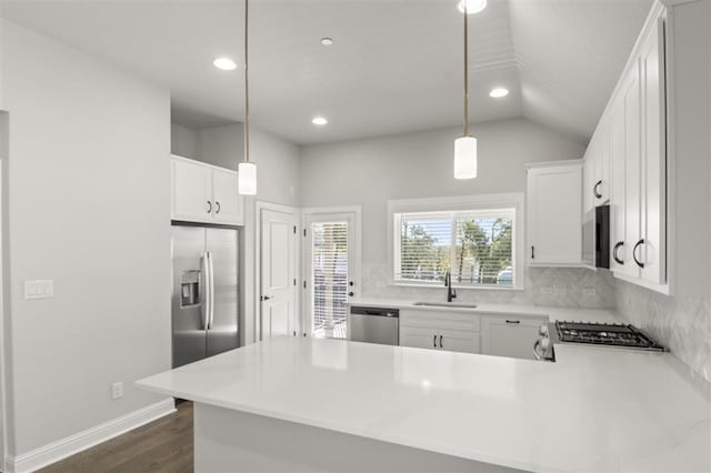 kitchen with kitchen peninsula, stainless steel appliances, hanging light fixtures, and vaulted ceiling