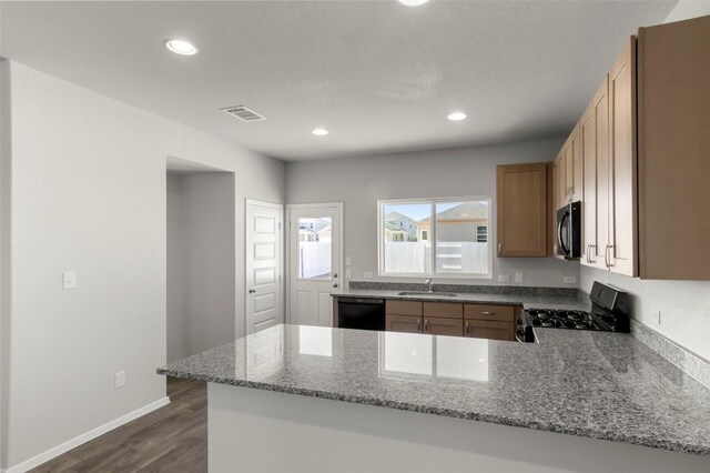 224 Barley Ln, Elgin, TX 78621 - kitchen featuring a peninsula, dishwasher, stainless steel microwave, gas stove, and dark wood-type flooring