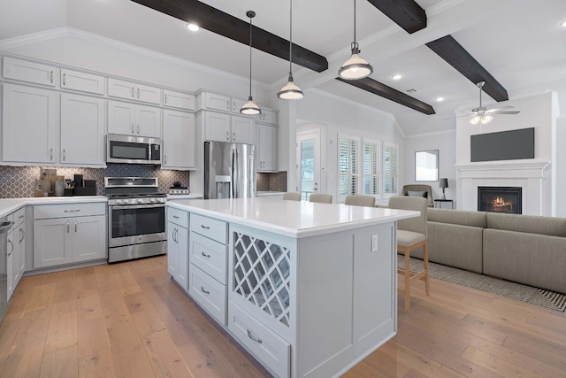 kitchen with beamed ceiling, light hardwood / wood-style floors, appliances with stainless steel finishes, and tasteful backsplash