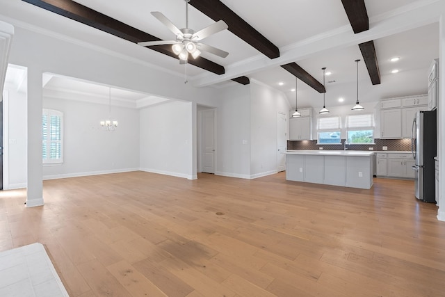 unfurnished living room featuring ceiling fan with notable chandelier, sink, light hardwood / wood-style flooring, ornamental molding, and beamed ceiling