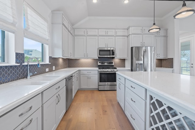 kitchen with pendant lighting, backsplash, sink, light wood-type flooring, and stainless steel appliances