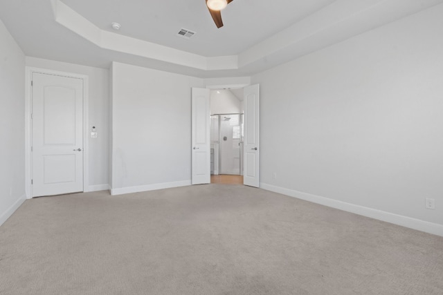 unfurnished bedroom with light colored carpet, a raised ceiling, and ceiling fan