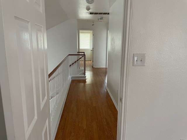 hallway featuring vaulted ceiling and dark hardwood / wood-style floors