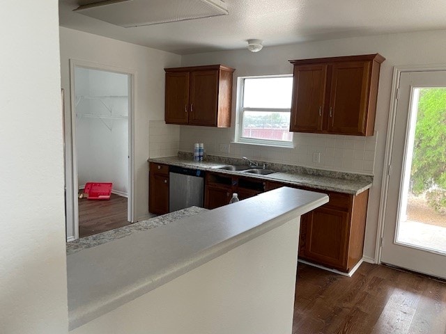 kitchen with decorative backsplash, dark hardwood / wood-style flooring, stainless steel dishwasher, and sink