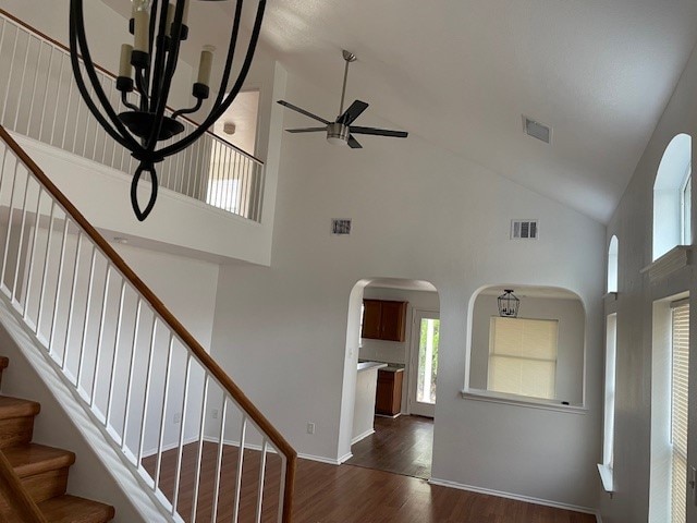 interior space with high vaulted ceiling, wood-type flooring, and ceiling fan with notable chandelier