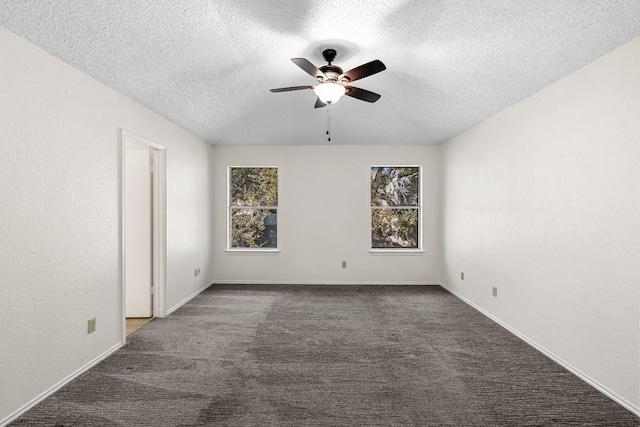 unfurnished room with ceiling fan, dark carpet, and a textured ceiling