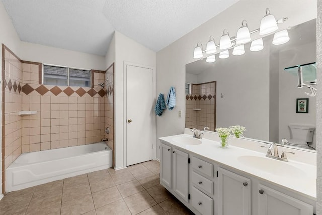 full bathroom featuring tile patterned flooring, vanity, a textured ceiling, tiled shower / bath, and toilet