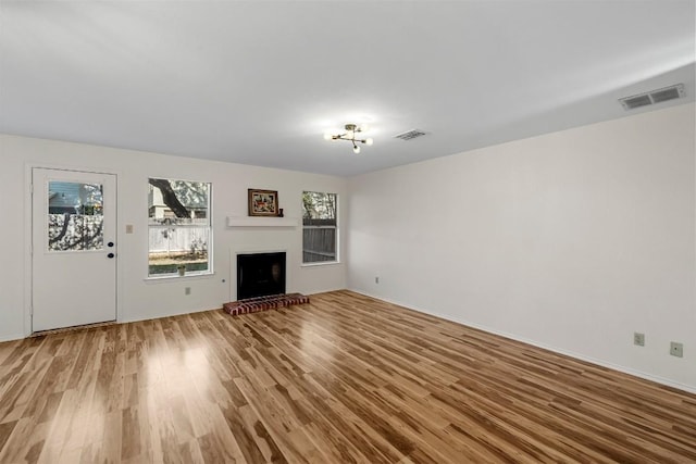 unfurnished living room featuring hardwood / wood-style flooring and a brick fireplace